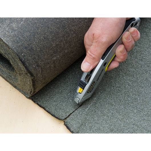 STANLEY 0-10-789 utility knife cutting grey roofing material, close-up photo of product in use.