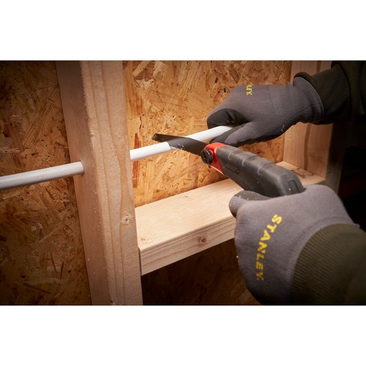 STANLEY 0-20-108 hand saw cutting white pipe, user wears Stanley gloves, photo at close angle.