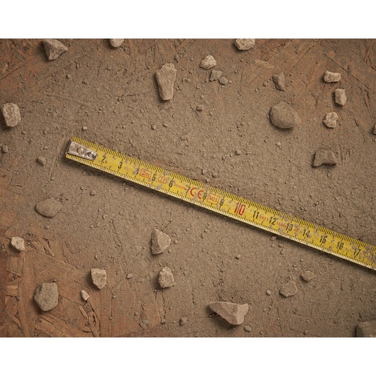 STANLEY 0-32-189 yellow tape measure on dusty ground with scattered rocks, top view photography.