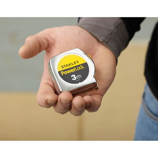 Photo of STANLEY 0-33-041 PowerLock 3m tape measure held in hand, silver case with yellow and black label.