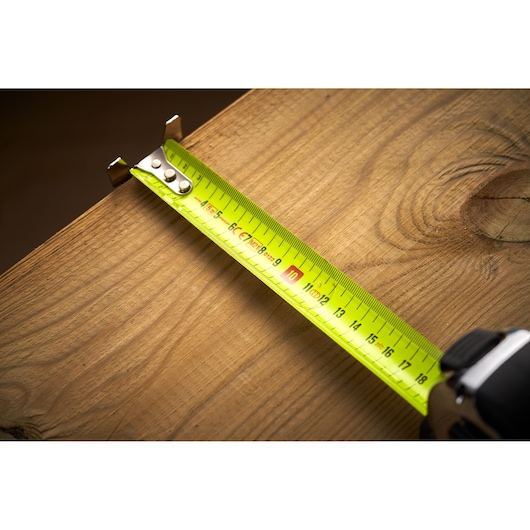 STANLEY 0-33-887 tape measure extended on wooden plank, close-up showing metric markings.