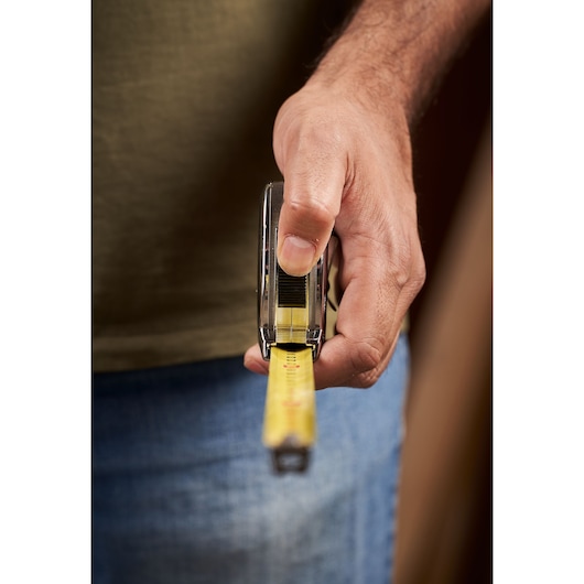 Photo of a person holding a STANLEY 0-33-932 tape measure, yellow blade extended, focus on hand and tool.