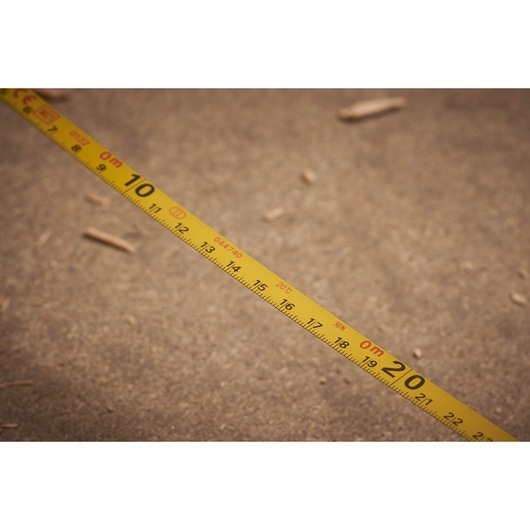 STANLEY 0-34-105 yellow measuring tape laid out on a brown surface, close-up view, Photography.