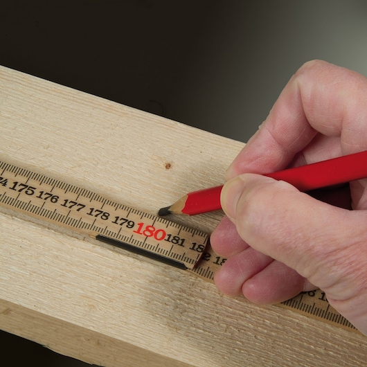 STANLEY 0-35-101 folding ruler measuring wood, red pencil marking at 180 cm, close-up photo.