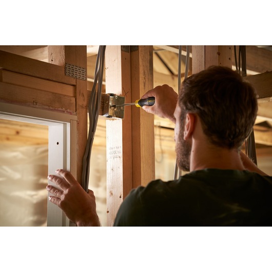 Photo of a person using a STANLEY 0-64-974 screwdriver to fasten an electrical box to wooden framing.