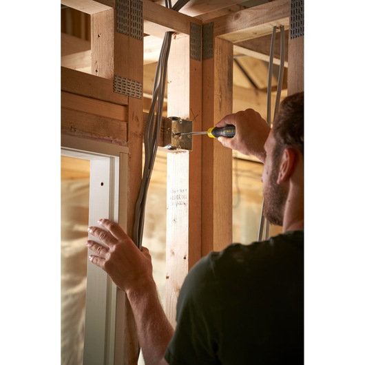 Person using STANLEY 0-64-974 screwdriver on electrical box during home construction.