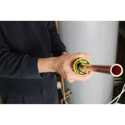 STANLEY 0-70-445 pipe cutter tool in use on a copper pipe, product held by person in workwear.