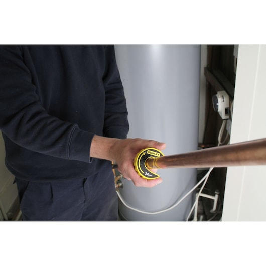 Photo of STANLEY 0-70-446 pipe cutter in use cutting copper pipe, held by person in work environment.