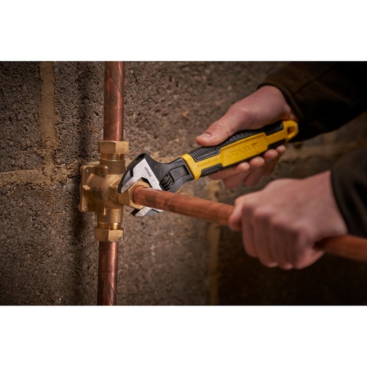 STANLEY 0-90-948 adjustable wrench used on copper pipe fitting, close-up, photography.