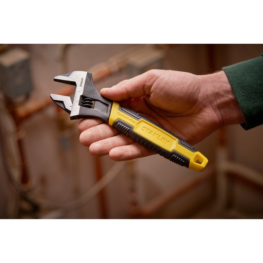 STANLEY 0-90-948 adjustable wrench with yellow and black ControlGrip handle held in a hand.