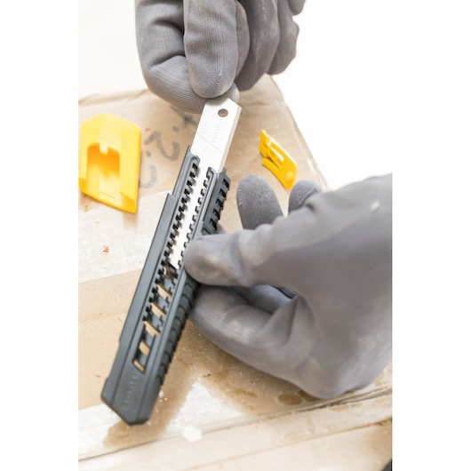 Photo of STANLEY 1-10-151 snap-off utility knife with black handle, gloves holding tool, yellow covers nearby.