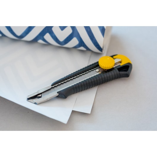 STANLEY 1-10-418 utility knife with black and yellow handle on paper, side view.