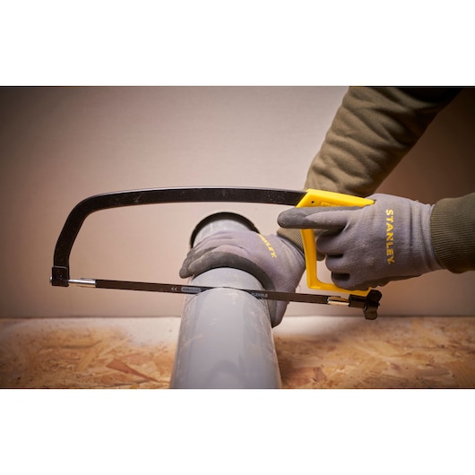 STANLEY 1-15-122 hacksaw with yellow handle cutting grey pipe, close-up angle, product photography.
