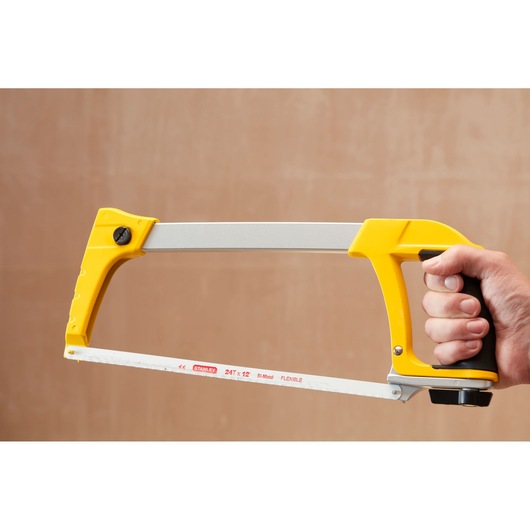 STANLEY 1-20-110 hacksaw with yellow handle, side view, held in hand, showing bi-metal blade.