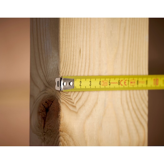 STANLEY 1-33-238 yellow tape measure extended against wooden beam, close-up angle.
