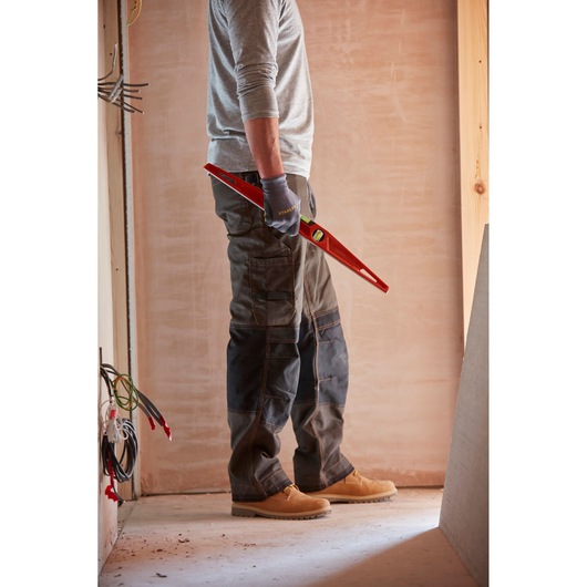 Photo of a person wearing work gloves holding a STANLEY 1-42-314 level tool at a construction site.