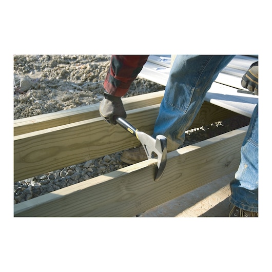 STANLEY 1-55-099 claw hammer used for framing on wooden beams, close-up, outdoor construction site.