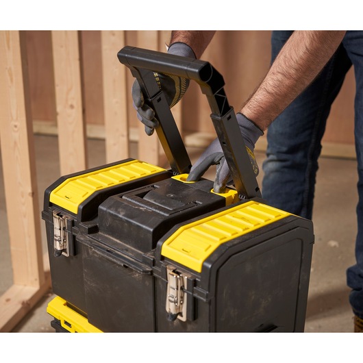 STANLEY 1-70-326 black and yellow rolling tool box close-up with handle extended, indoor setting.