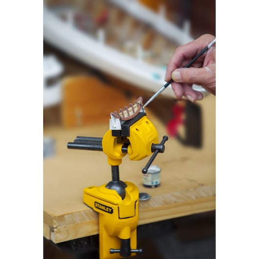 STANLEY 1-83-069 bench vice clamped to a table, holding a small model while being painted.