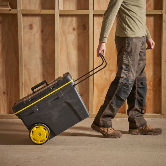 STANLEY 1-92-904 rolling toolbox with yellow wheels being pulled by a person in a workshop.