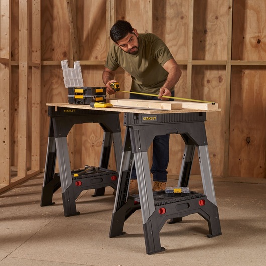 Photo of STANLEY 1-92-980 sawhorse pair used as workbench in a workshop with tools and wood plank.