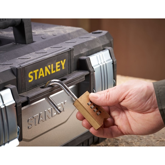 Photo of STANLEY 1-95-618 toolbox being locked with a brass combination padlock.