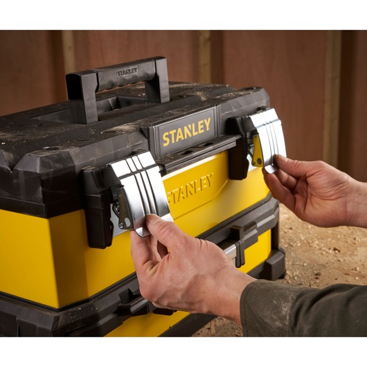 STANLEY 1-95-829 toolbox with metal latches, hands opening yellow and black case, product close-up.