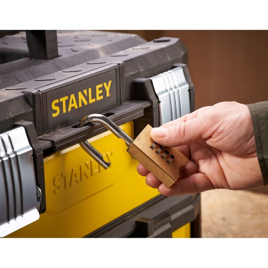 STANLEY 1-95-829 toolbox close-up, yellow and black, with open combination padlock held by a hand.