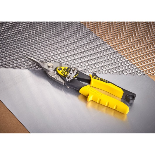 STANLEY 2-14-563 aviation snip with yellow handle on metal mesh and sheet, angled view.