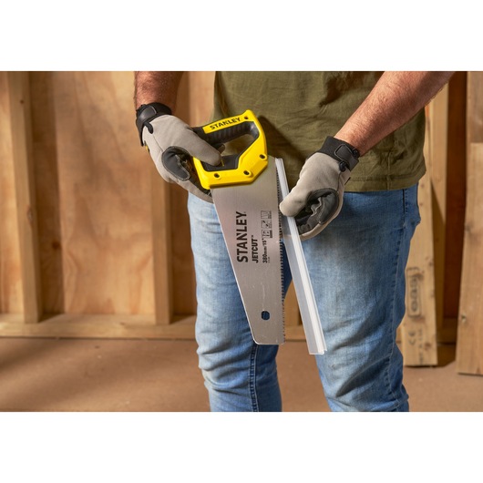 STANLEY 2-15-281 hand saw with yellow handle, photographed in use cutting a white plastic profile.