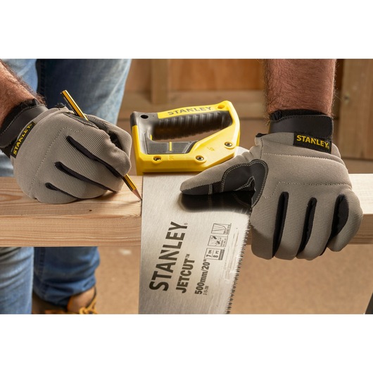 Photo of STANLEY 2-15-288 hand saw and gloves marking wood, with yellow saw handle visible in workshop.
