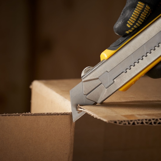 STANLEY 3-11-725 utility knife cutting cardboard box, close-up photography.