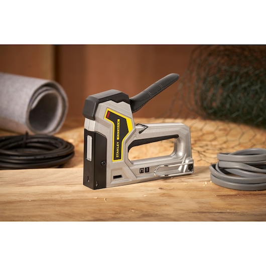 STANLEY 6-TR350 heavy-duty stapler side view on wooden surface with rolled materials in background.