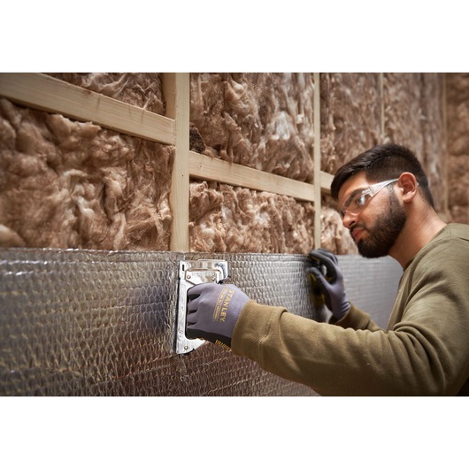 Photo of STANLEY 6-TR45 staple gun being used to attach insulation to a wall, close-up of hand and tool.
