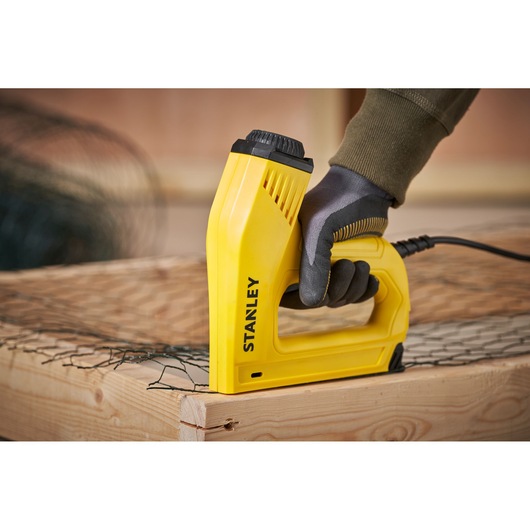Stanley 6-TRE550 electric stapler, yellow, side angle, used on wood and wire mesh.