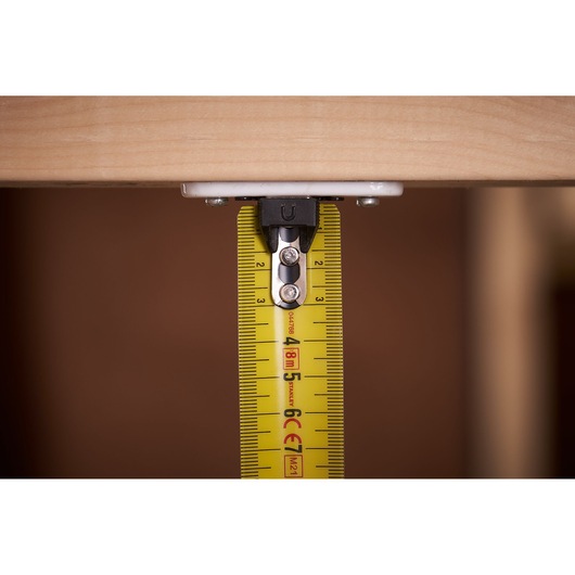 STANLEY FMHT0-33868 tape measure close-up measuring wood edge, yellow blade visible.