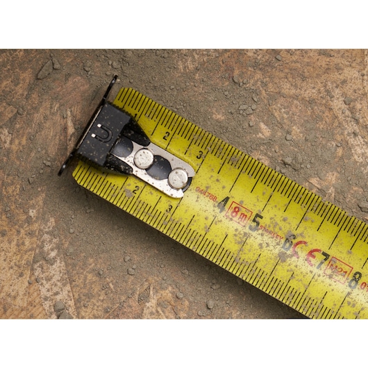 STANLEY FMHT0-33868 yellow tape measure close-up on dusty surface, showing centimeter markings.