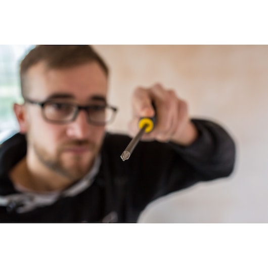 STANLEY FMHT0-62060 screwdriver with yellow and black handle held in hand, close-up view.