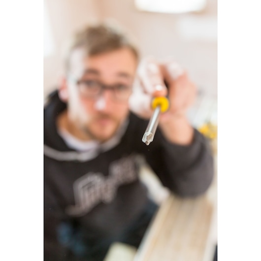 Photo of STANLEY FMHT0-62060 screwdriver with yellow handle held in hand, focus on tip.