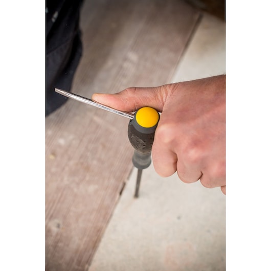 Photo of a hand using a STANLEY FMHT0-62060 screwdriver with a black and yellow handle on a wood surface.