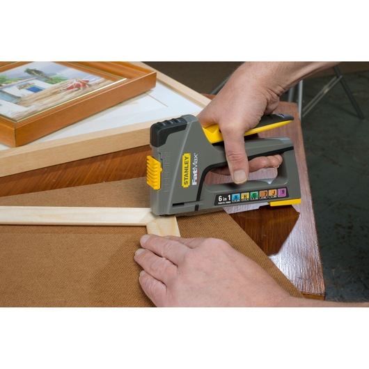 STANLEY FMHT0-70868 hand stapler in use on wooden frame, close-up, showing yellow and gray design.