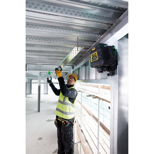 STANLEY FMHT1-77441 laser level mounted on steel beam in construction site, worker aligning metal bracket.