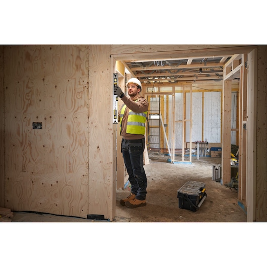 STANLEY FMHT43673-1 spirit level used by worker on wooden door frame at construction site.