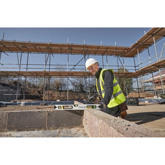Stanley FMHT43673-1 spirit level used by worker on construction site, measuring brick wall.