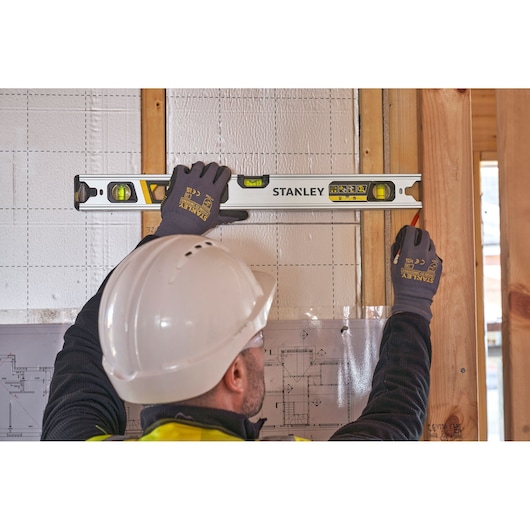 Photo of a worker using a STANLEY FMHT43673-1 spirit level on a wall frame at a construction site.