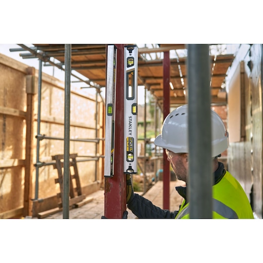 STANLEY FMHT43673-1 spirit level being used vertically on construction site by worker in safety gear.