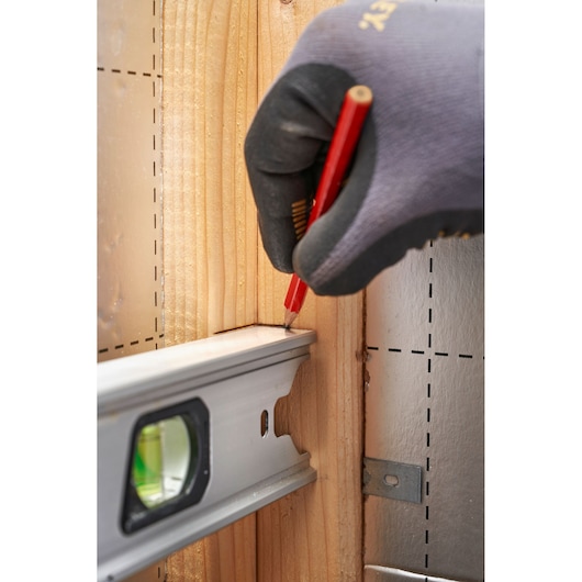 STANLEY FMHT43673-1 spirit level, side angle, marking on wood with pencil and gloved hand.