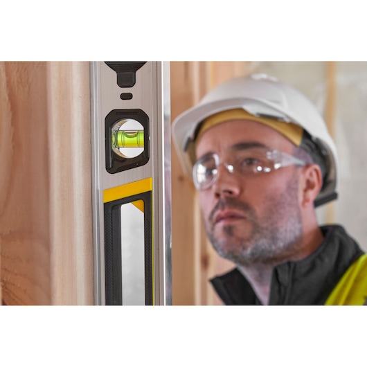 STANLEY FMHT43673-1 spirit level close-up, yellow and black details, in use at construction site.