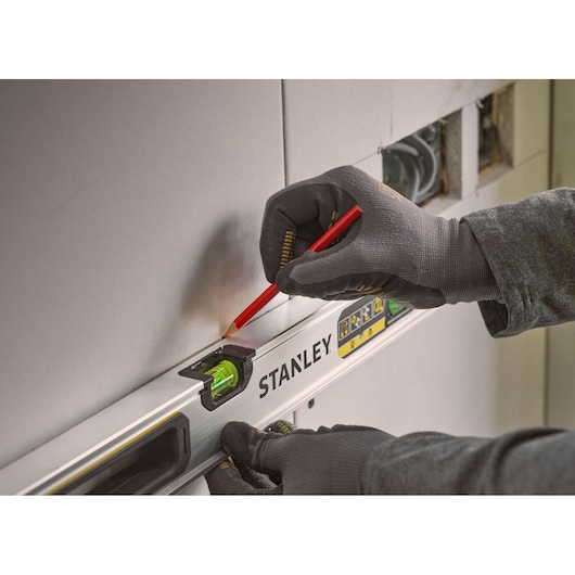 Stanley FMHT43673-1 spirit level in use, close-up, hand marking wall with pencil.