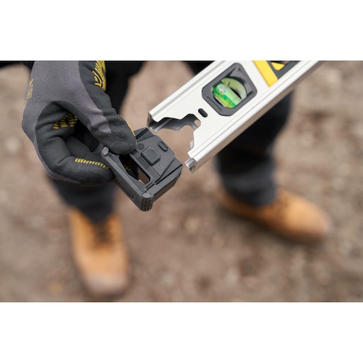 STANLEY FMHT43673-1 photography of laser level adapter held by gloved hand near spirit level outdoors